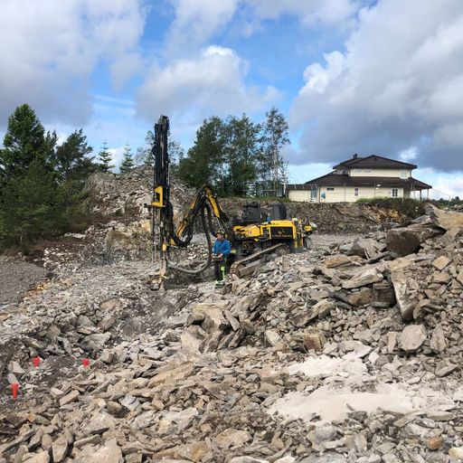 Gravemaskin blandt steiner på dagtid